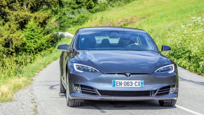 Tesla kører på landevej i naturen