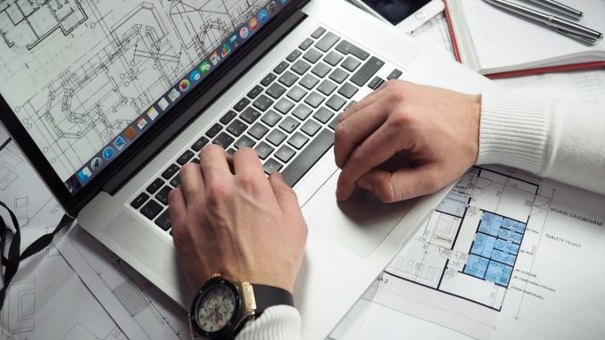Mand designer arkitektur på sin computer