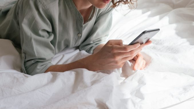 Kvinde bruger sin telefon i sin seng